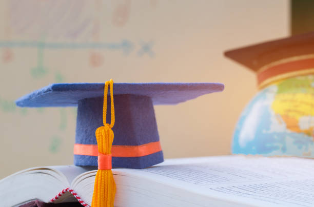Graduate or Education knowledge learning study abroad concept : Graduation cap on opening textbook with blur of america earth world globe model map in Library room of campus, Back to School graduado o el conocimiento de la educación aprendizaje de concepto en el extranjero de estudio: cap de graduación en libro de texto de apertura con desenfoque de américa tierra globo modelo mapamundi en sala de biblioteca del campus, regreso a la escuel