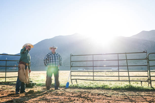 istock Early morning sunlight over mountains ranchers talking pointing and looking over field 990954492