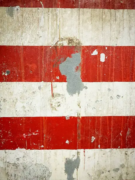 Peeling red-and-white striped painted surface as industrial background.