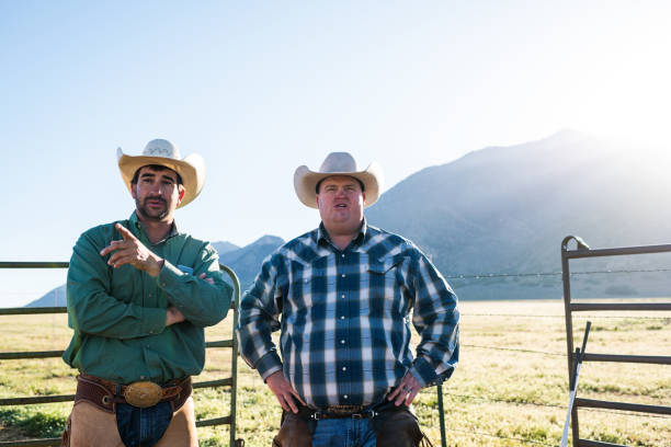 istock Mid shot early morning sunlight over mountains ranchers talking pointing looking over field 990957036