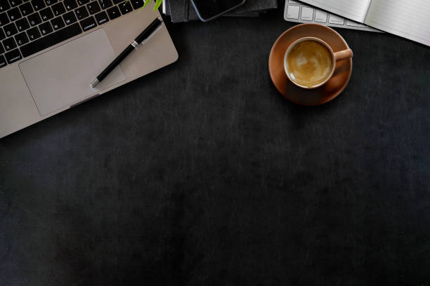 istock Workspace office leather dark desk with laptop, office supplies and coffee cup. Top view with copy space 990957082