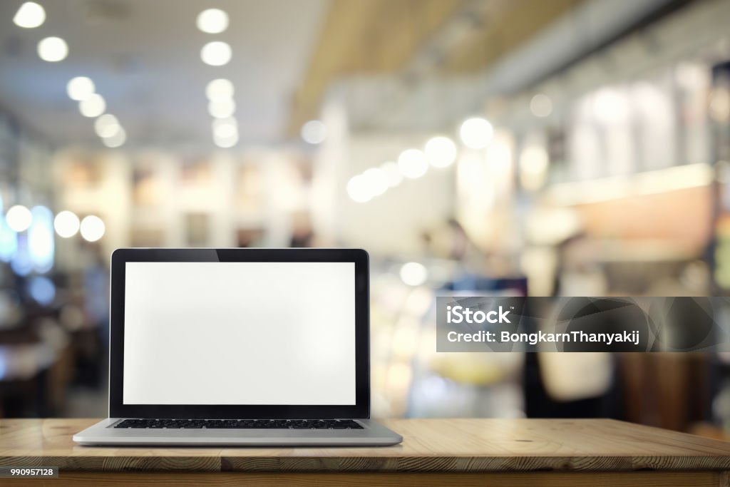 Laptop with blank screen on wooden table with blur cafe, restaurant backgrounds. Laptop Stock Photo