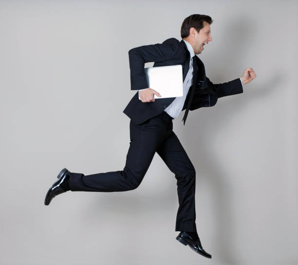 istock Businessman in full suit jumping with laptop 990962260