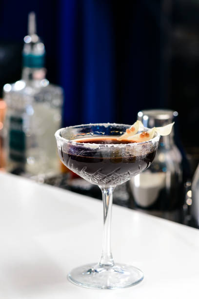 istock Black alcoholic cocktail in martini glass on blue background, sh 990972488