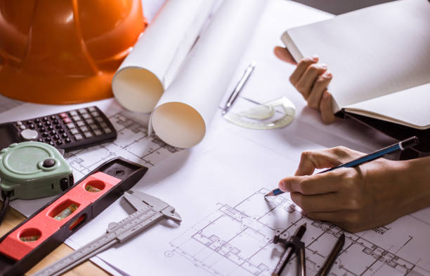istock Concept architects,engineer holding pen pointing equipment architects On the desk with a blueprint in the office, Vintage, Sunset light.Selective Focus 990975686