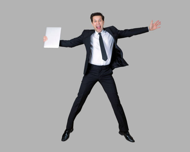 istock Businessman in full suit jumping with laptop 990975798