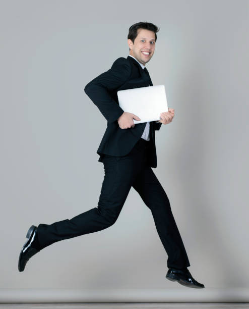 istock Businessman in full suit jumping with laptop 990980192