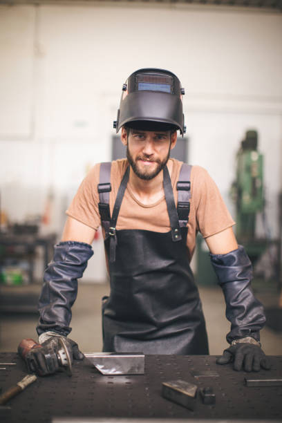 istock Young professional welder grinding and welding metal bars 990986224