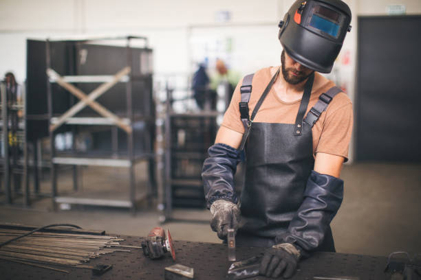 istock Young professional welder grinding and welding metal bars 990988592