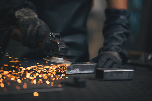 istock Young professional welder grinding and welding metal bars 990990916