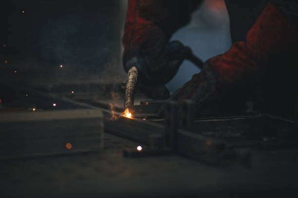 istock Young professional welder grinding and welding metal bars 990991780