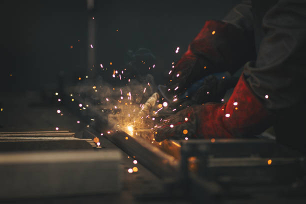 istock Young professional welder grinding and welding metal bars 990992190