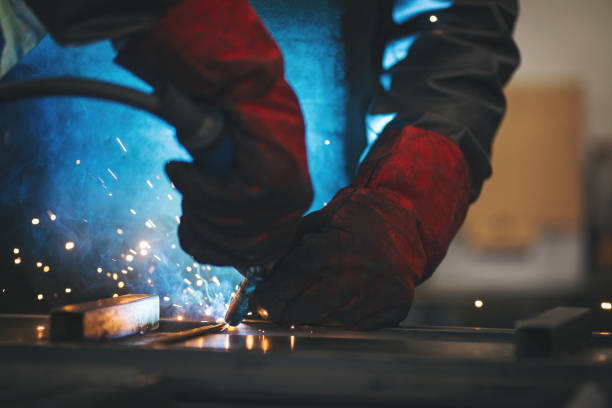 istock Young professional welder grinding and welding metal bars 990992438