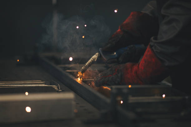 istock Young professional welder grinding and welding metal bars 990994146