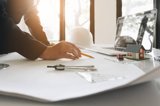 istock Engineer or Architect concept, Image of engineer drawing a blue print design building or house, An engineer workplace with blueprints, pencil, protractor and safety helmet, Industry concept 990997906