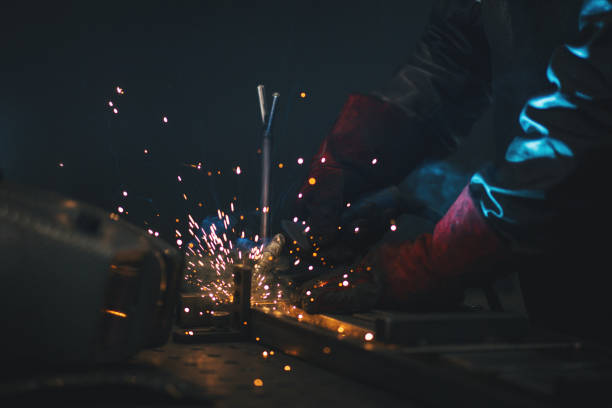 istock Young professional welder grinding and welding metal bars 991000724