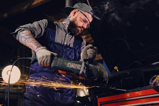 istock Mechanic cuts steel car part with an angle grinder. 991005238
