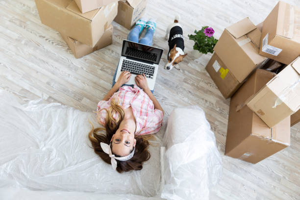 istock Young woman with dog lying on sofa using laptop 991006956