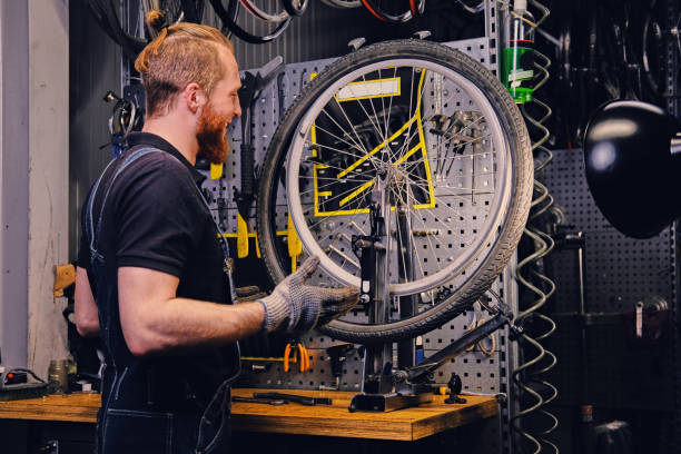 istock Mechanic repairing bicycle wheel tire in a workshop. 991013316