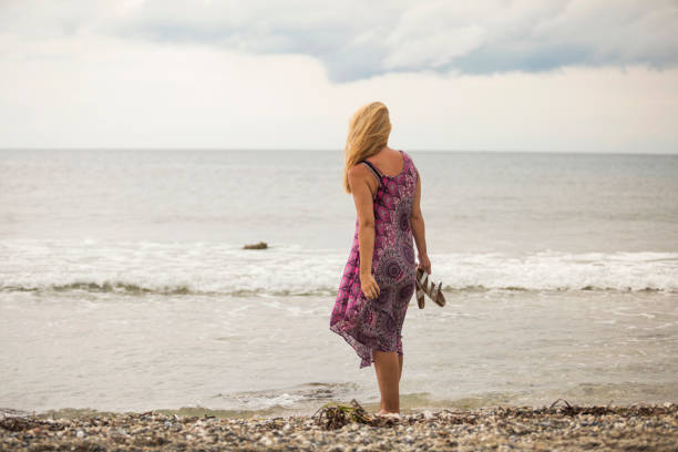 istock Woman walking alone on the beach 991030466