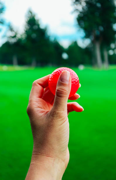 гольф розовый мяч держать в руке женщины, зеленая трава конечно, голубое небо. - golf women pink ball стоковые фото и изображения