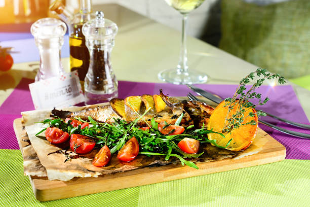 istock Delicious fish served with tomatoes, lemon and herbs on the wood 991032032