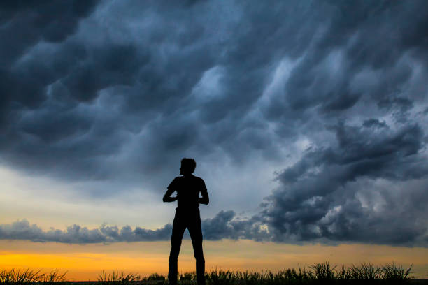istock A young man alone holding his camera against a dramatic sky at dusk. 991041632