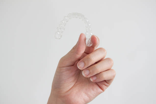 Invisalign braces Hand holding clear invisalign braces on white background, new technology of dental equipment tooth in hand stock pictures, royalty-free photos & images