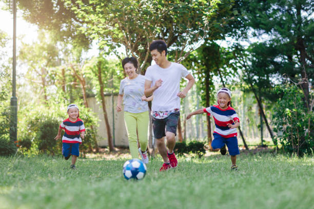 istock Family playing soccer in public park 991051952