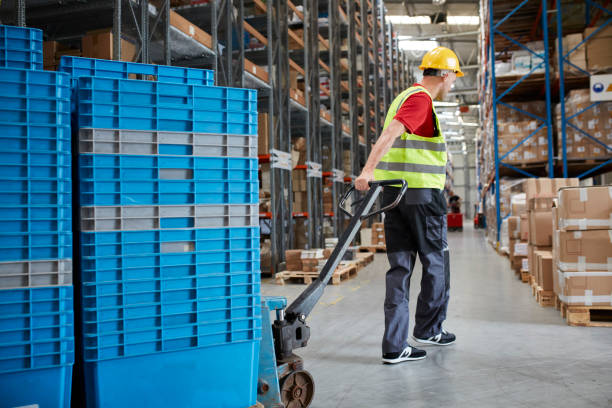 istock Warehouse worker walking among shelves with handcart 991053284