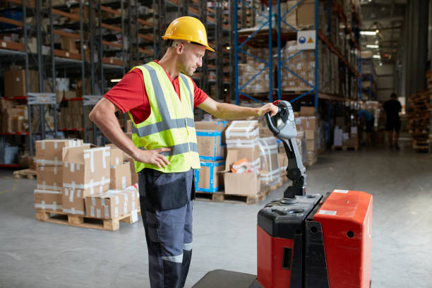 istock Warehouse worker walking among shelves with handcart 991053454