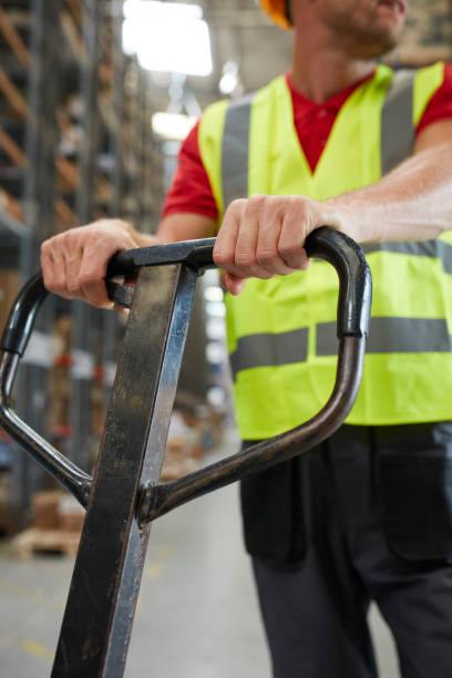 istock Warehouse worker standing among shelves with handcart 991055642