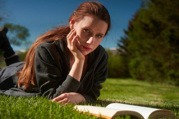 istock Beautiful woman relaxing on the grass with book 991056530