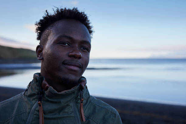istock Young man looking at view. Black beach 991057296