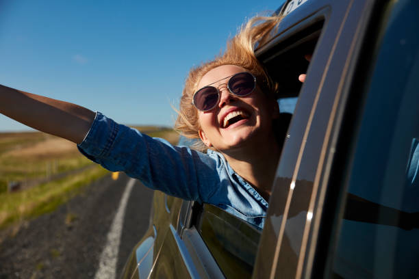 istock Playful woman on road trip. Catching wind 991057458