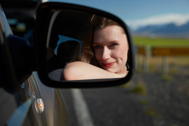 istock Woman on road trip. Reflecting in a car mirror 991057784