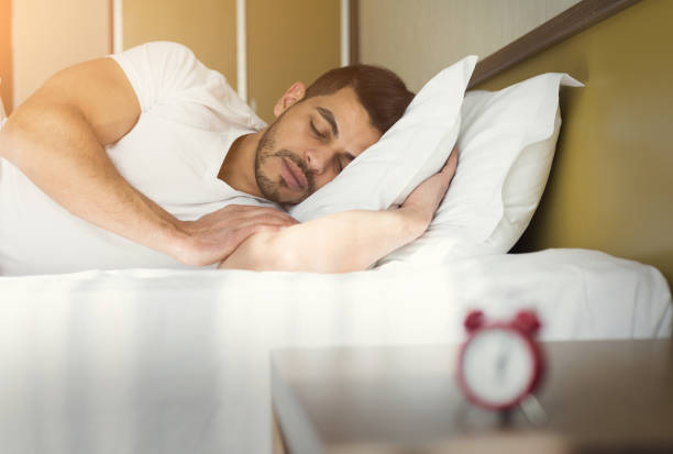 side view of handsome man sleeping in bed - clock face fotos imagens e fotografias de stock