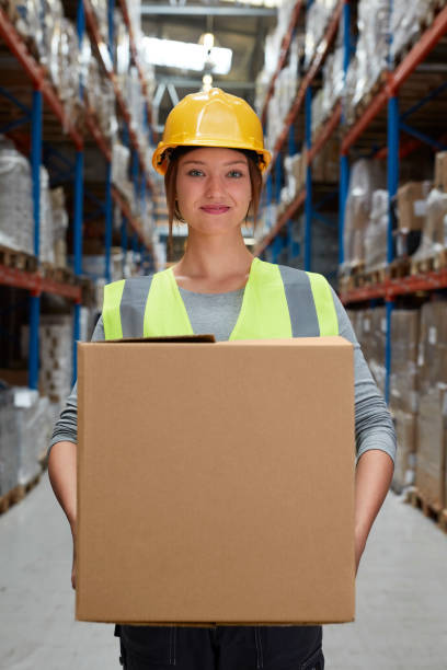 istock Woman working at a warehouse. Carrying heavy boxes 991058208