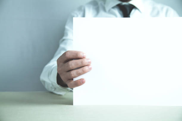 istock Businessman holding blank white paper for advertise text. 991072852