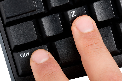 Closeup foto de dos dedos masculinos pulsando control + z acceso directo en un teclado de computadora inalámbrico desktop negro photo