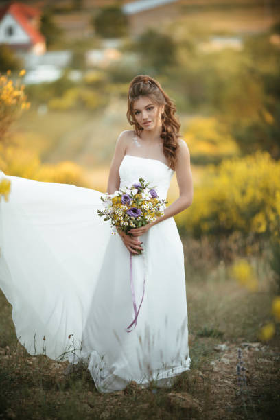 Hermosa Joven Novia Lleva Vestido Blanco Con Moda Ramo De Flores Silvestres En Campo Amarillo Concepto De Boda Natural Foto de stock y más banco de imágenes de Adulto - iStock Hermosa Joven Novia Lleva Vestido Blanco Con Moda Ramo De Flores Silvestres En Campo Amarillo Concepto De Boda Natural Foto de stock y más banco de imágenes de Adulto - iStock