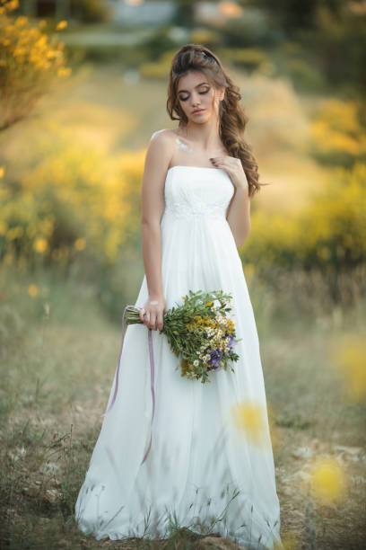 Bella Sonriente Novia Lleva Ramo De Explotación De Vestido De Moda Blanco De Flores Silvestres En Campo Amarillo Concepto De Boda Natural Foto de stock y más banco de imágenes de Adulto - Bella Sonriente Novia Lleva Ramo De Explotación De Vestido De Moda Blanco De Flores Silvestres En Campo Amarillo Concepto De Boda Natural Foto de stock y más banco de imágenes de Adulto -