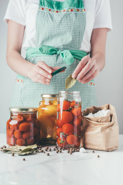 istock cropped image of woman adding bay leaf to preserving tomatoes at kitchen 991088304