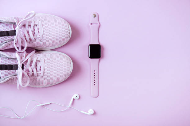 фиолетовые кроссовки, наушники и часы на розовом фоне. - vibraphone стоковые фото и изображения