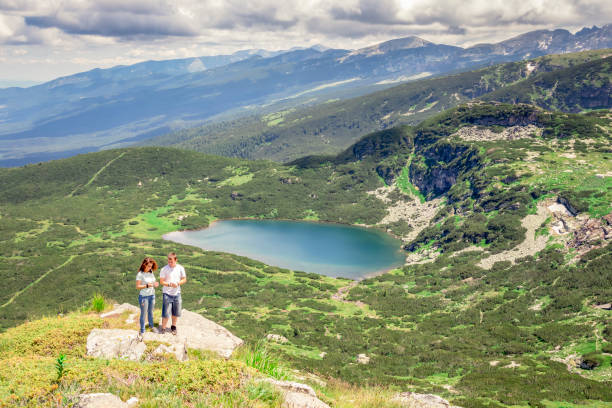 istock Couple on mountain peak taking picture 991096052