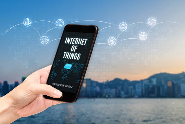 istock Hand holding mobile with Internet of things (iot) word on screen with icon feature glowing in air with blur city building background,Digital Lifestyle concept. 991100024