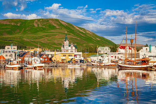 Scenic view of the historic town of Husavik in beautiful golden evening light at sunset with blue sky and clouds, north coast of Iceland