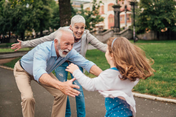 granddaughter running into arms of her grandparents - grandparent grandfather grandmother child imagens e fotografias de stock