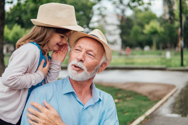 hombre escucha a su nieta susurro le - whispering grandparent child grandfather fotografías e imágenes de stock