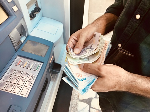 Hombre Turco manos dando dinero al cajero automático photo